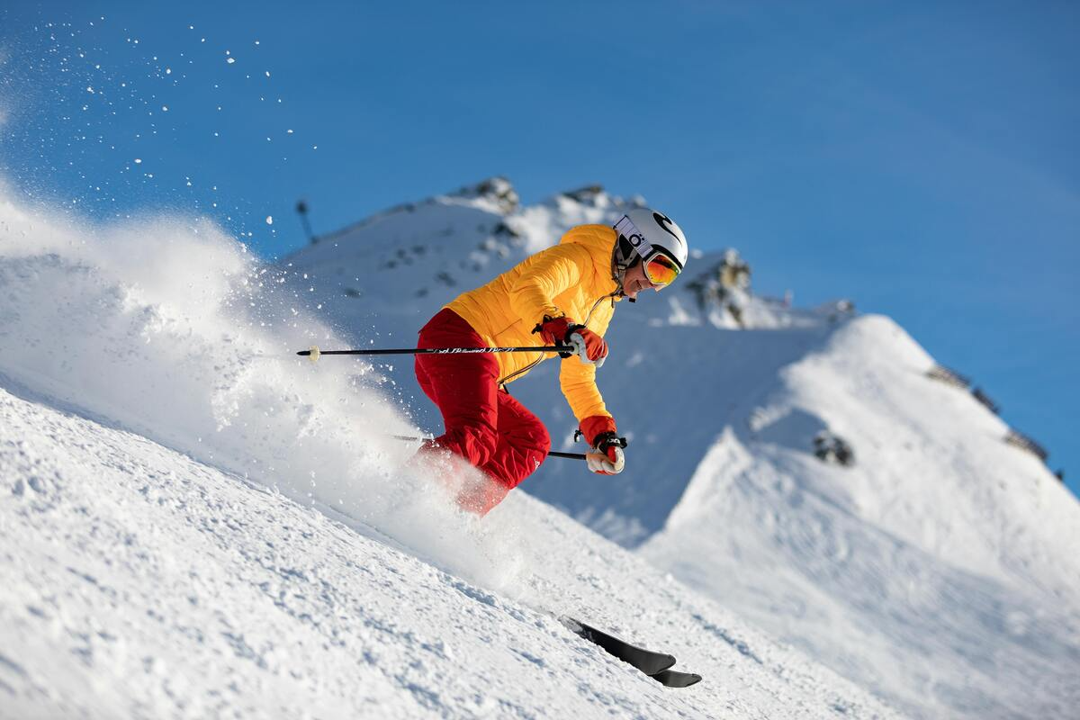 A skier carving down a snowy mountain slope on a clear winter day.