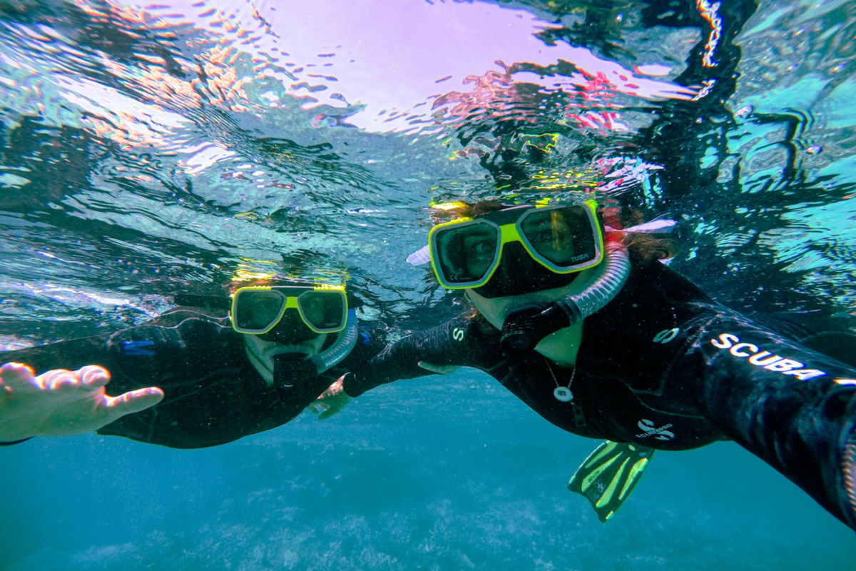 Two scuba divers looking straight at an underwater camera.