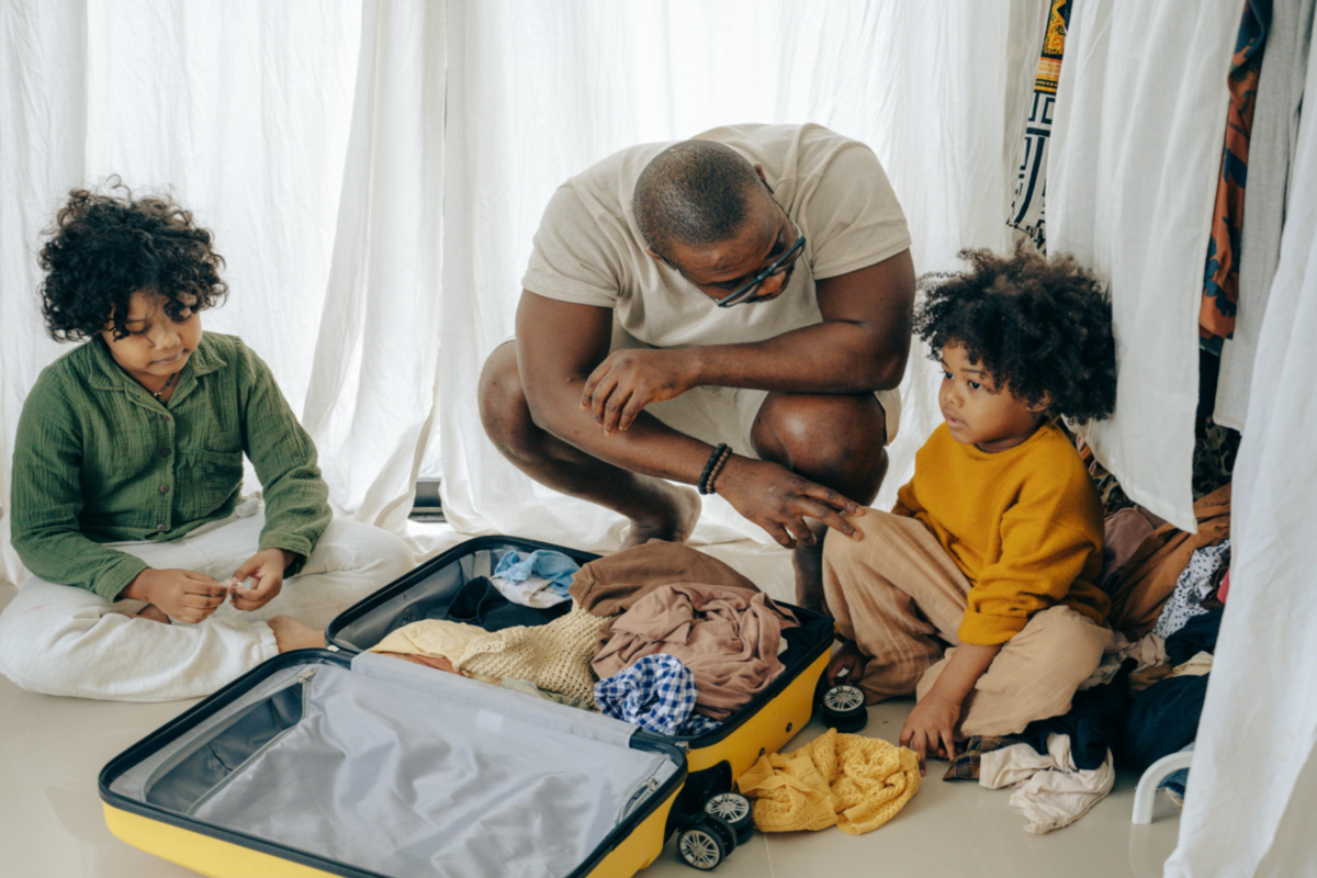 A parent packing a suitcase for family travel with his children.