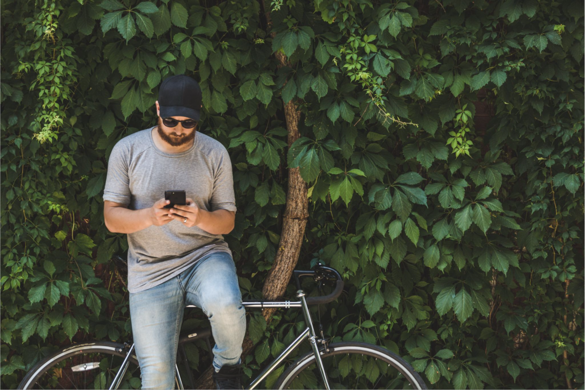 A person resting on their bike, looking at their smartphone.