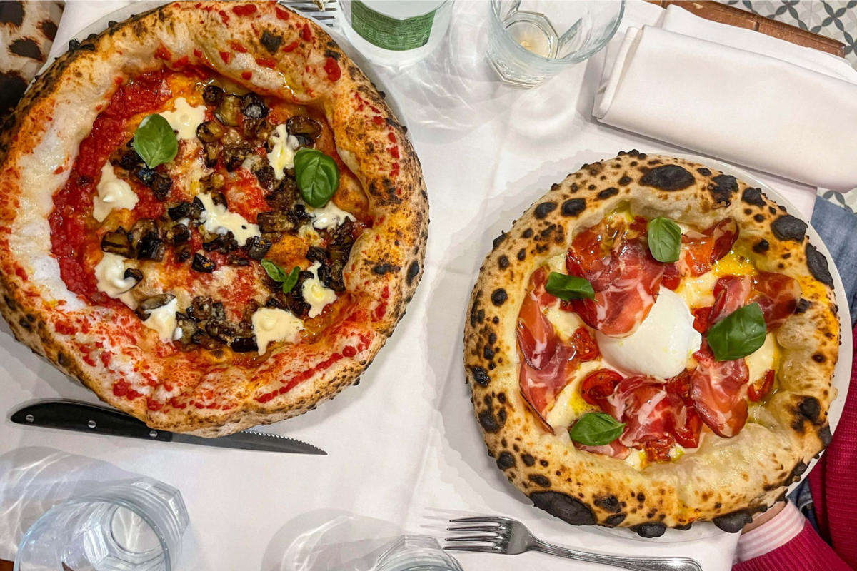 Bird’s eye view of two Italian vegetarian pizzas.