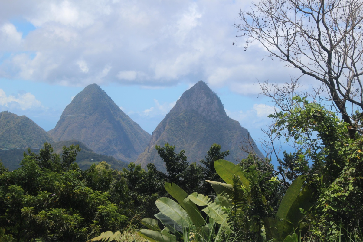 View of Saint Lucia with the iconic Pitons rising from the coastline surrounded by lush rainforest.