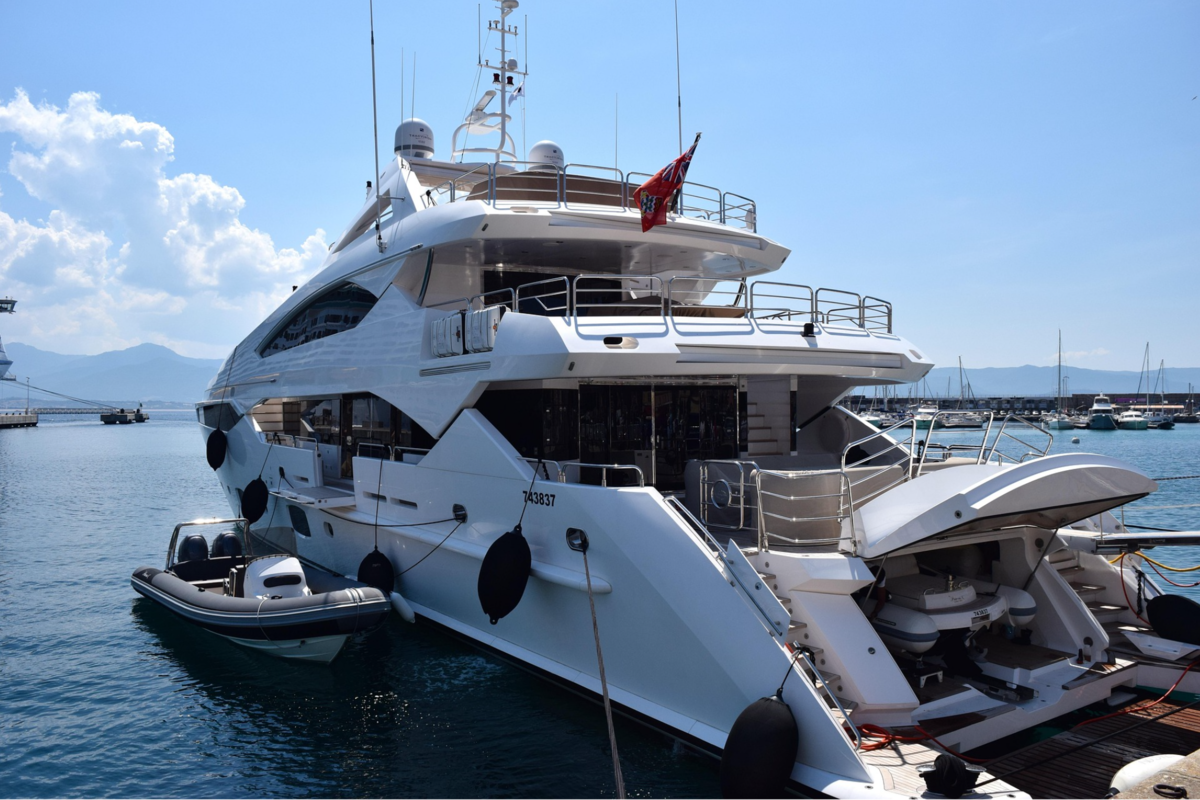 Luxury motor yacht berthed in a Mediterranean marina, with a tender moored alongside. 