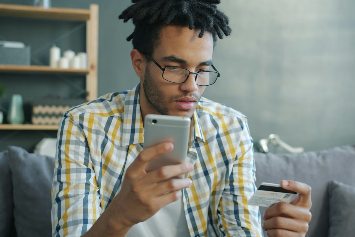 A man holding and looking intently at a phone and an ID card.