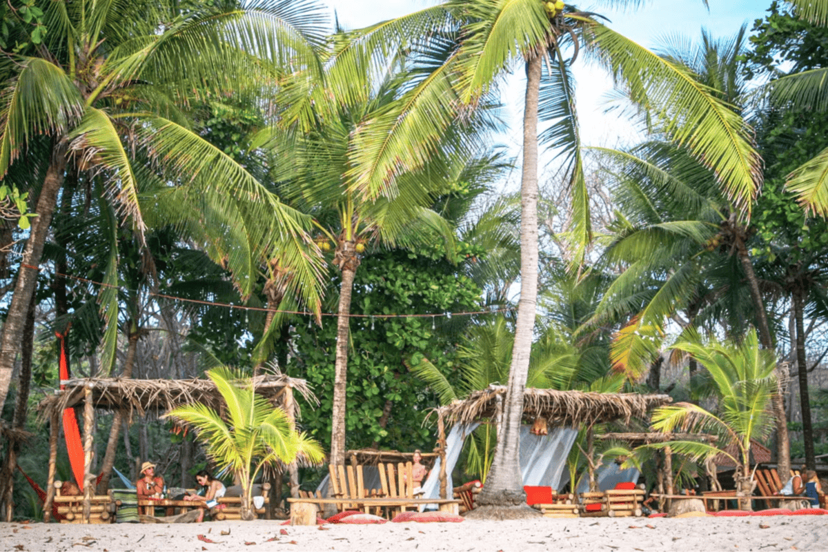 People lounging in wooden cabanas on a Costa Rica beach.
